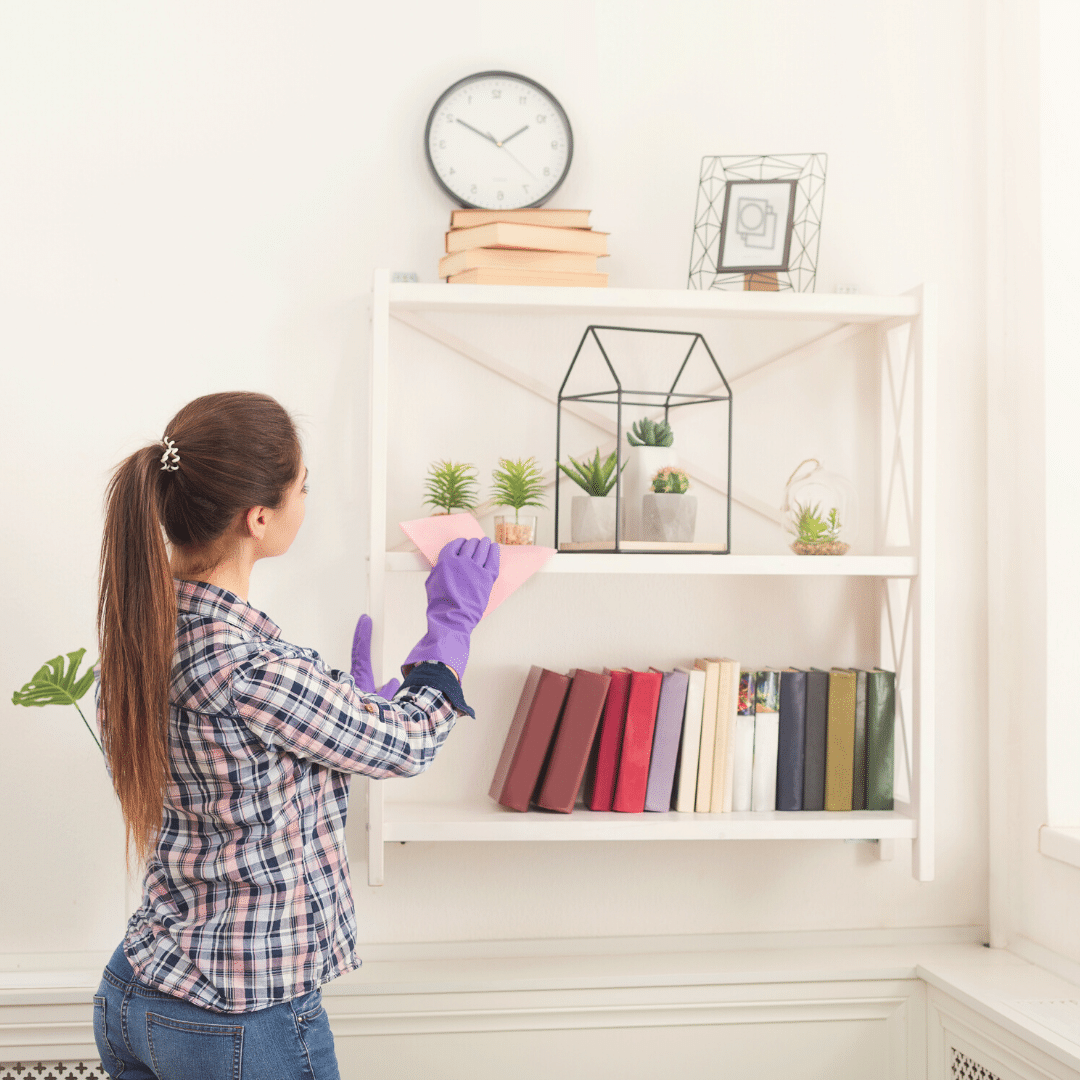 Woman cleaning bookshelves to stay productive during a lockdown 